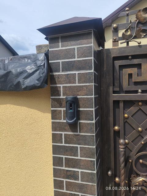 Виклична панель домофона на цегляному стовпі біля воріт